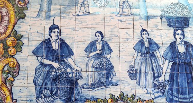 Mural de azulejos azulejería azul y blanco que muestra mujeres tradicionales con canastas de productos.