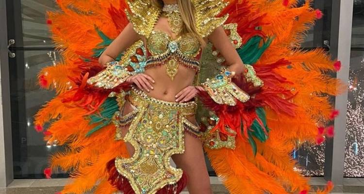Mujer vistiendo un elaborado traje de carnaval con plumas y joyas posando en interiores