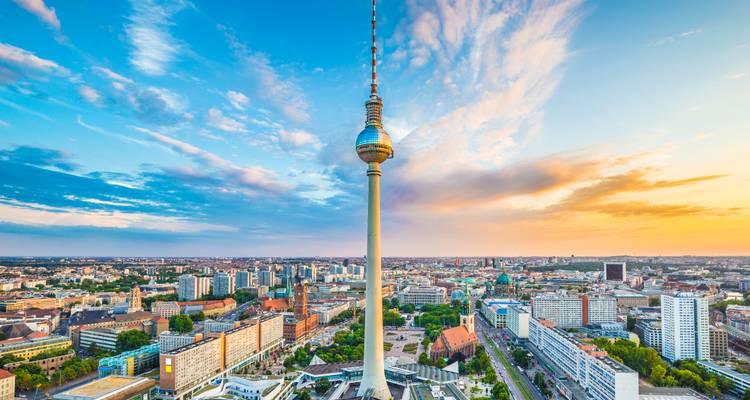 Paysage urbain panoramique de Berlin avec la tour Fernsehturm perçant le ciel lors d'un coucher de soleil coloré.