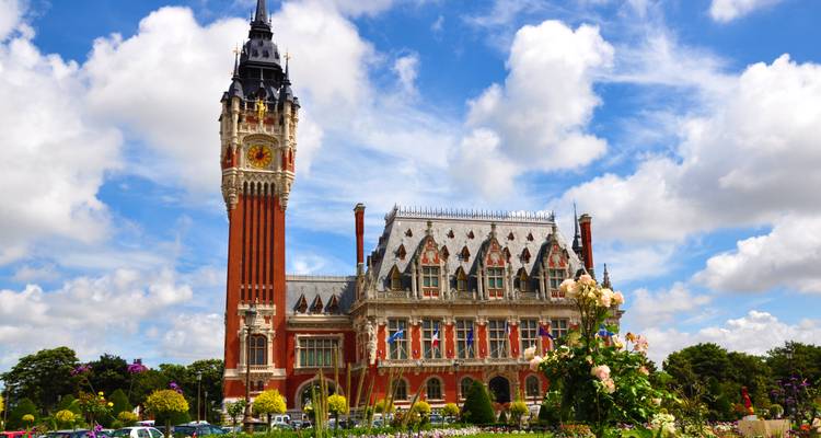 Das prächtige rote Backsteinrathaus von Calais mit seinem hohen Glockenturm und angelegten Gärten unter flauschigen Wolken.