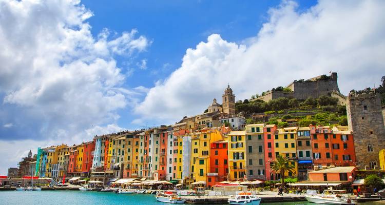 Los coloridos edificios frente al mar y las barcas alinean el puerto de Portovenere bajo nubes dramáticas.