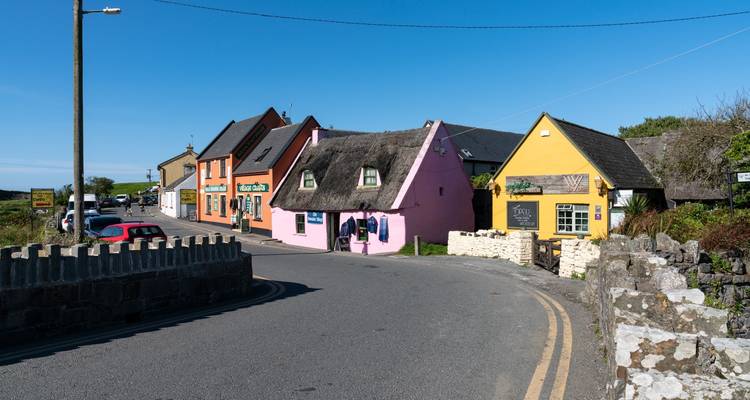 Rangée pittoresque de petits chalets aux toits de chaume aux couleurs vives à Doolin par une journée dégagée.