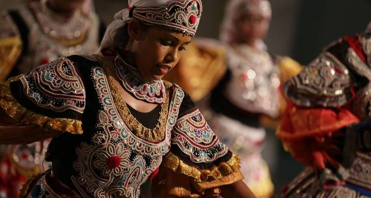 Danseuse sri-lankaise traditionnelle en costume orné, capturée en pleine représentation.