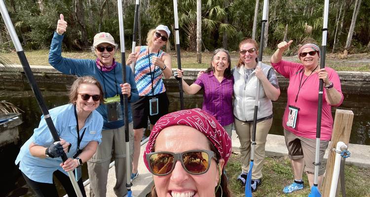 Des femmes souriantes tenant des pagaies posent pour un selfie avant une aventure de pagayage.