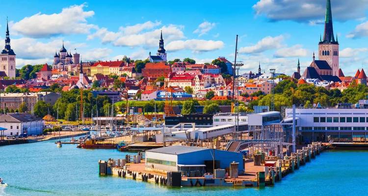 Skyline coloré de Tallinn avec des flèches d'église s'élevant derrière un port animé et un terminal de ferry.