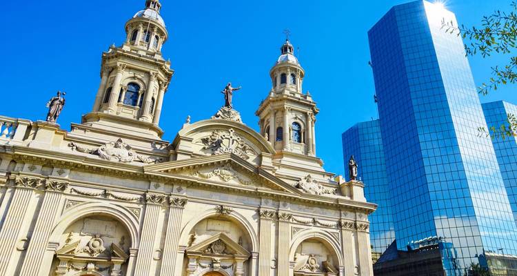 Fachada de la Catedral Metropolitana de Santiago con un rascacielos moderno de vidrio elevándose a su lado.