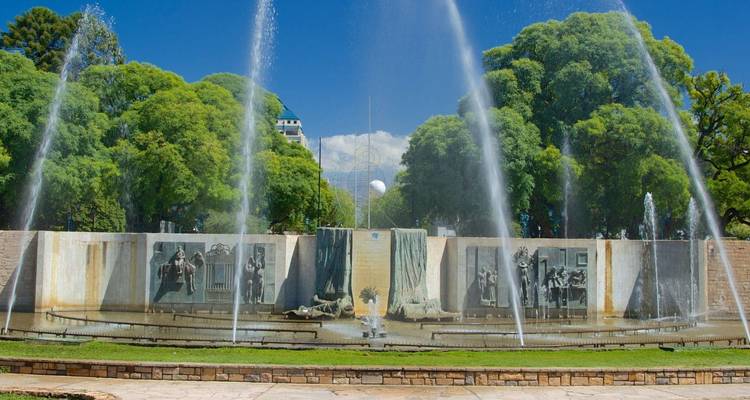 Los chorros de agua danzantes se elevan frente a relieves murales en un parque de la ciudad de Buenos Aires a la sombra.