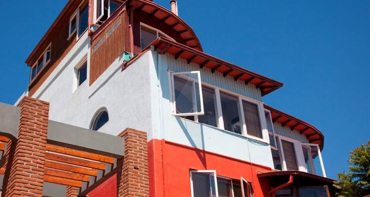 Kleurrijk, meerdelig huis van Pablo Neruda in Valparaíso tegen een heldere blauwe lucht.