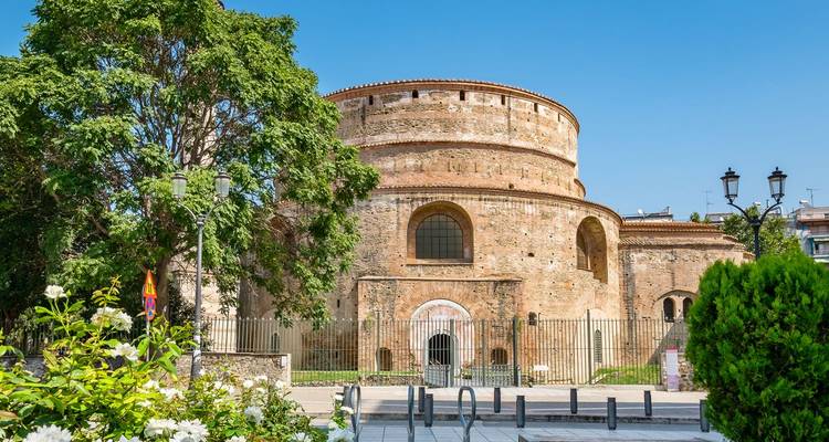 Bakstenen Rotunda-monument omringd door groene bomen en heldere blauwe lucht in Thessaloniki.