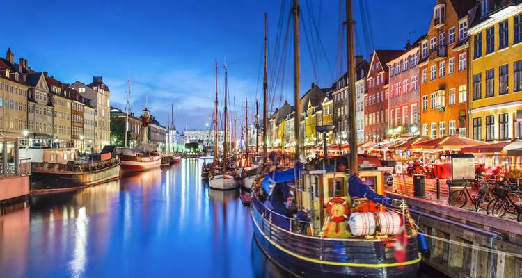 Nyhavn-kanaal omzoomd met levendige gebouwen en aangemeerde zeilboten verlicht in de schemering