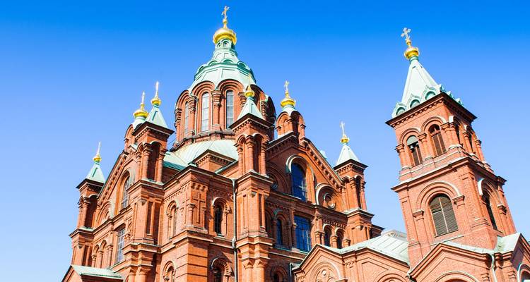 Catedral ortodoxa de ladrillos rojos con cúpulas de cobre verde y cruces doradas contra un cielo despejado