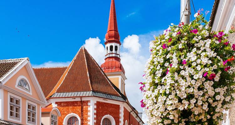 Charmante straat in een Baltische stad met rode dakpannen op de kerktoren en een bloeiende hangende bloemmand