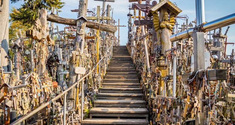Houten trap met duizenden kruisen en cruciﬁxen die een heuvel op gaan