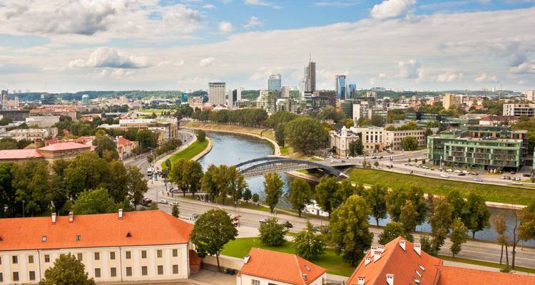 Panoramisch uitzicht over een rivier die zich slingert door een moderne Baltische stad met groene parken
