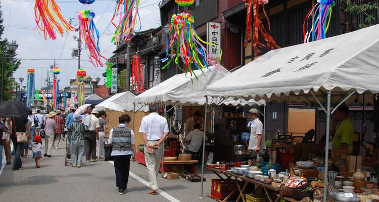 Druk openluchtmarktstraat met feestversieringen, kramen en winkelende bezoekers