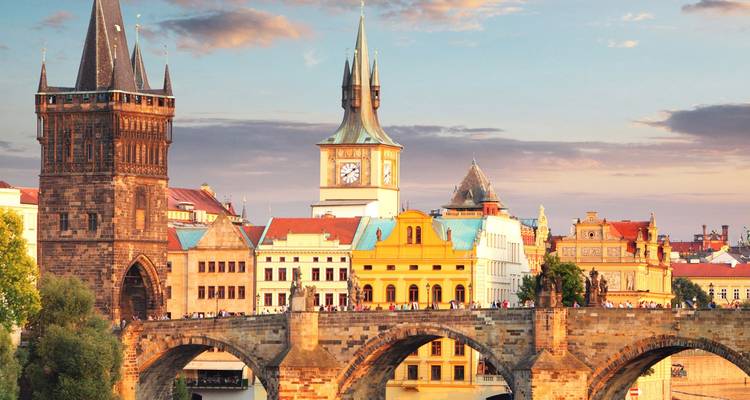 Photo prise à l'heure dorée du pont Charles de Prague avec ses tours historiques et un ciel aux tons pastel