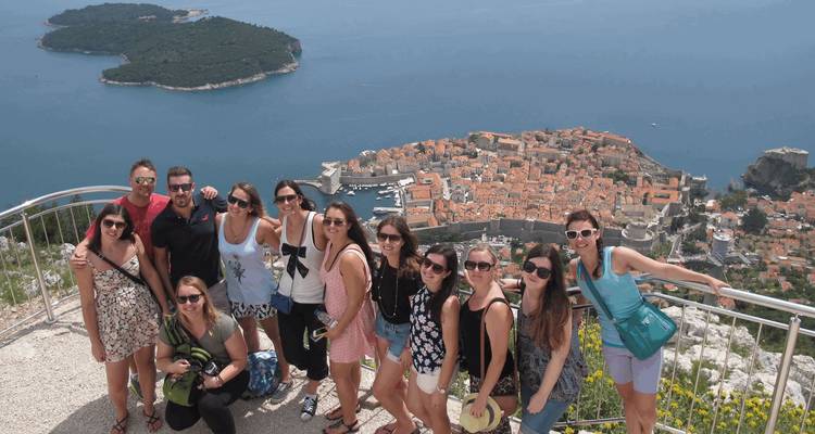 Gruppe junger Reisender, die an einem hohen Aussichtspunkt über der Altstadt von Dubrovnik und der Adria posieren