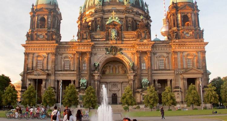 Berlijnse Kathedraal in warm licht gehuld met fontein en mensen die ontspannen op het grasveld