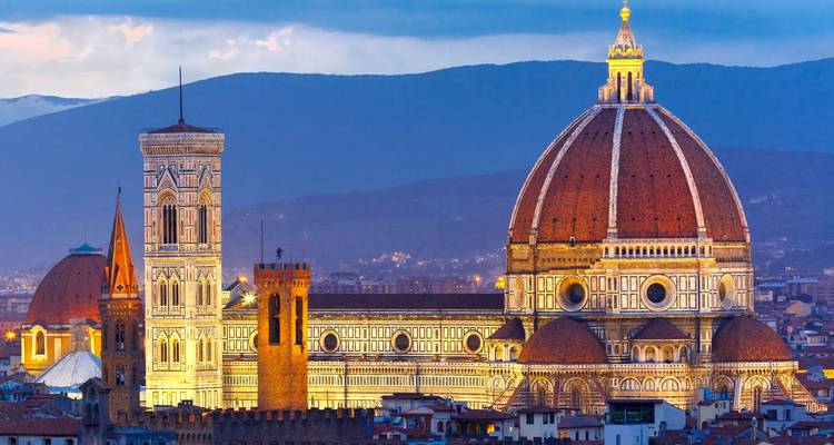 De verlichte Duomo van Florence en de klokkentoren staan majestueus tegen de schemering bergen.