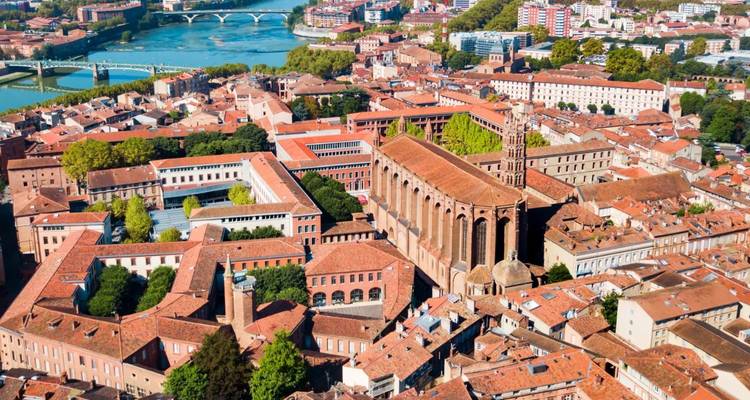 Luchtfoto van Toulouse's rode dakpannen, indrukwekkende bakstenen basiliek en de kronkelende Garonne rivier.