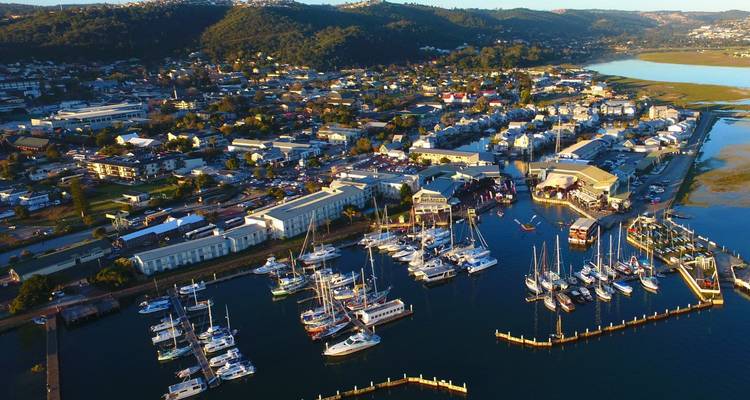 Vista aérea de la marina de Knysna con yates agrupados y el pueblo extendiéndose hacia las colinas circundantes.