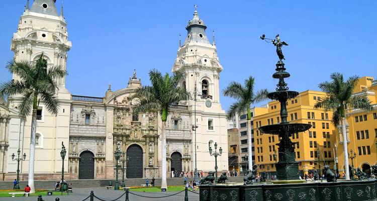 De Kathedraal van Lima en een sierlijke bronzen fontein sieren het historische Plaza de Armas met palmbomen.