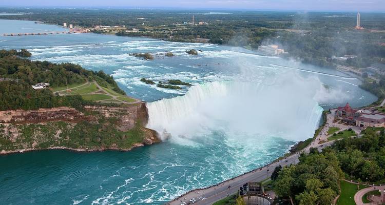 Vista aérea amplia de las Cataratas Herradura en el Niágara con niebla elevándose y exuberante vegetación rodeando la garganta.