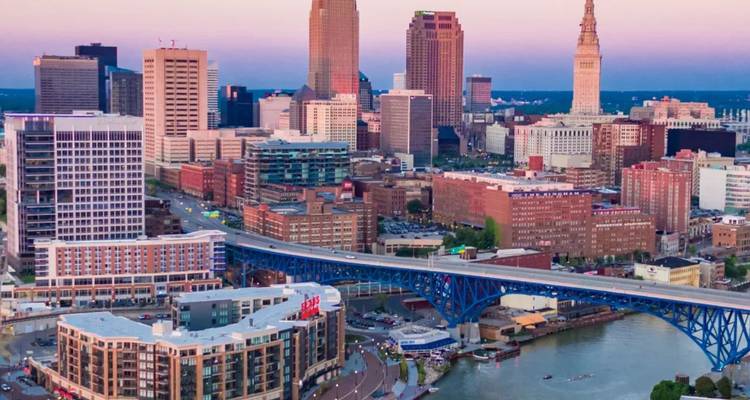 Paisaje urbano de Cleveland al atardecer con el puente Hope Memorial arqueándose sobre el río Cuyahoga.