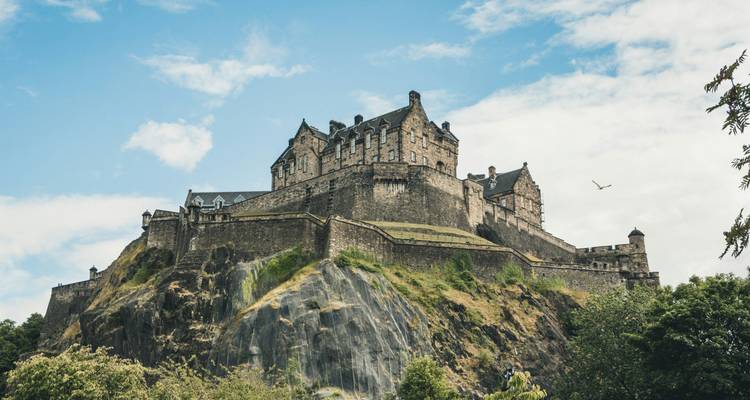 El histórico Castillo de Edimburgo encaramado en lo alto de Castle Rock contra un cielo parcialmente nublado