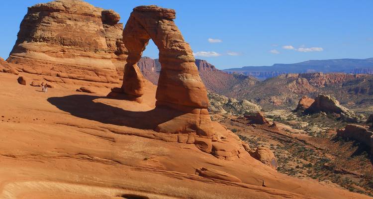 Iconic Delicate Arch rises above swirling sandstone in a vast desert vista.