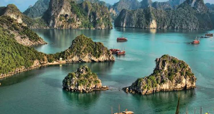 Scenic vista of limestone islets rising from calm turquoise water in Halong Bay.
