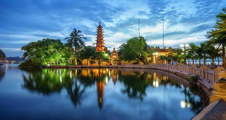 Tran Quoc Pagoda glows at blue hour, its reflection shimmering on the lake surface.