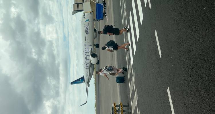 Les voyageurs traversent le tarmac de l'aéroport en direction d'un avion Azores Airlines sous un ciel nuageux.