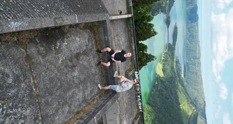 Deux amis posent sur les ruines d'un toit avec vue sur les lacs vibrants de Sete Cidades bien en contrebas.