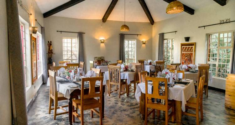 Cozy lodge dining room with wooden tables set for dinner, large windows and rustic beams.