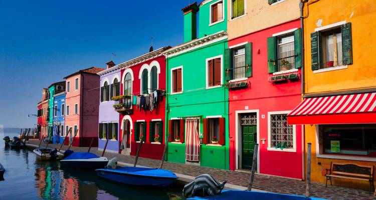 Canal bordé de maisons aux couleurs vives et de bateaux amarrés sur l'île de Burano, Venise.