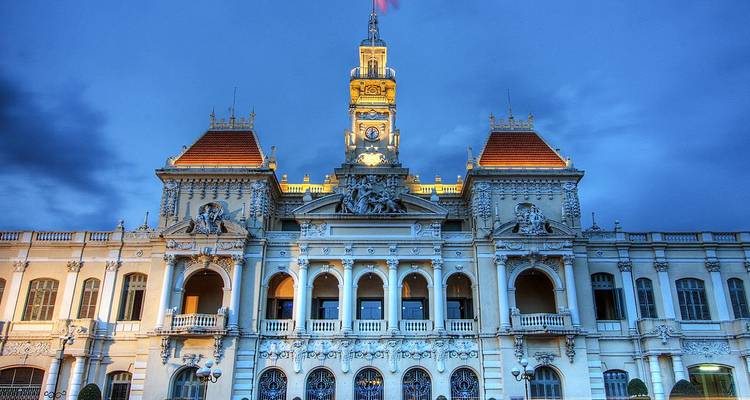 Illuminated French colonial Ho Chi Minh City Hall against the deep blue evening sky.