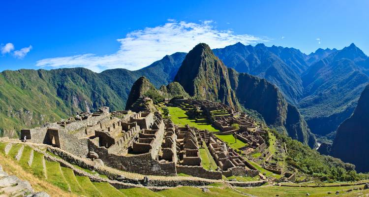 Ikonische Ruinen von Machu Picchu auf einem Bergrücken gelegen mit dramatischen Gipfeln dahinter