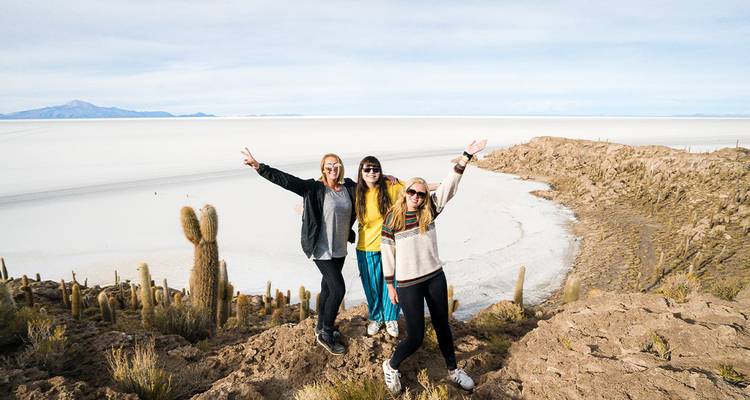 Trois amis posent sur un affleurement rocheux surplombant le vaste Salar de Uyuni.