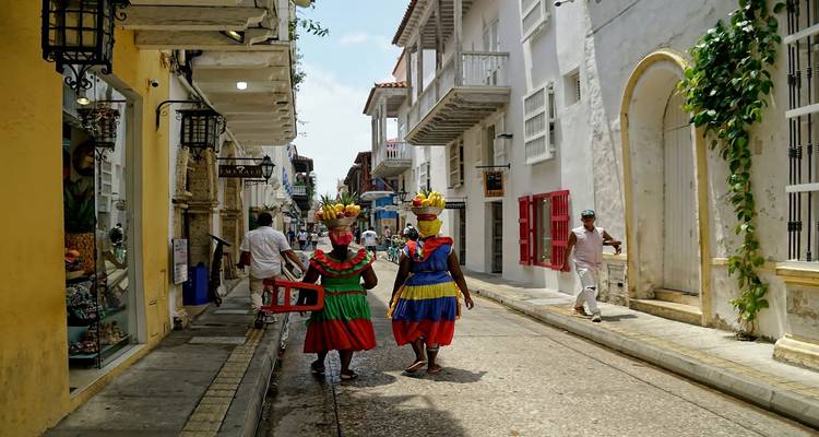 Colorful colonial street in Cartagena with fruit-bearing palenqueras walking away