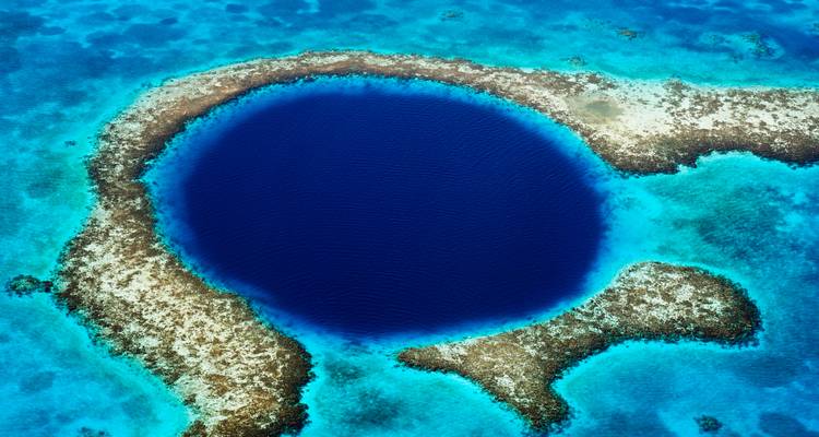 Vue aérienne spectaculaire du Grand Trou Bleu de Belize, entouré d'une barrière de corail turquoise et de mer cristalline.