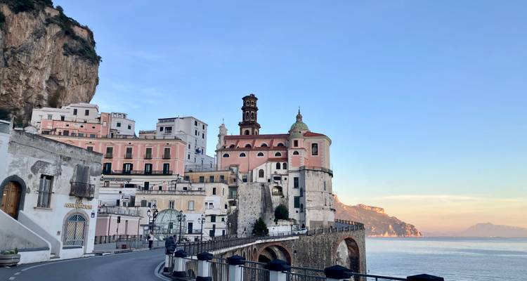 Picturesque coastal village with pastel buildings and a church tower built into a cliff above the sea