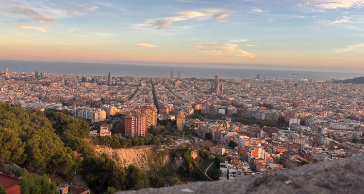 Vue panoramique large de Barcelone s'étendant jusqu'à la Méditerranée depuis une colline élevée.