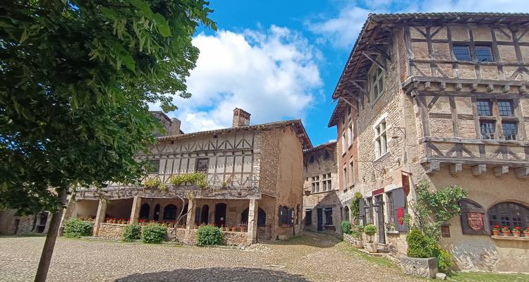 Place médiévale charmante avec des maisons à colombages et des balcons fleuris sous un ciel bleu