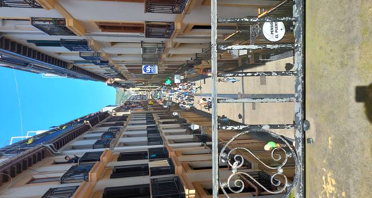 Rue piétonne dynamique vue d'en haut, remplie de personnes et bordée de balcons.