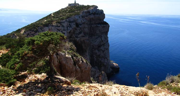 Scharfkantiges Kalksteinvorgebirge, das sich in das tiefblaue Meer erstreckt und von einem kleinen Leuchtturm gekrönt wird.