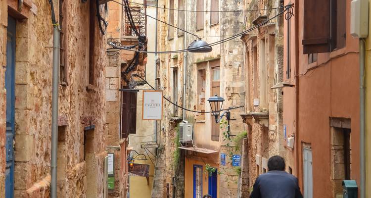 Narrow stone alleyway lined with rustic buildings and tangled cables in the old town of Chania.