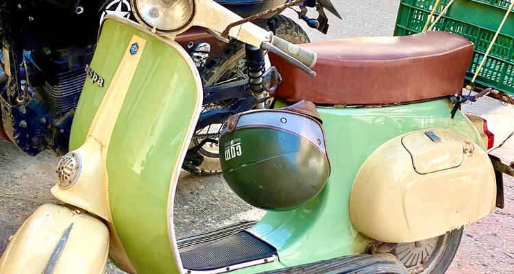 Scooter Vespa bicolore vintage garé dans une rue de la ville.