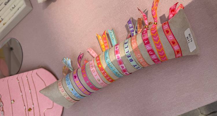 Des bracelets en tissu brodé coloré disposés sur un rouleau d'exposition à un marché de rue.