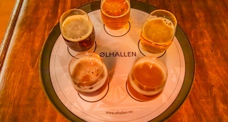 Cinq verres de dégustation de bière artisanale sur un plateau Ølhallen de marque.